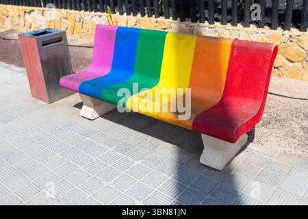 Colorful concrete bench, a striking piece of urban art. Bench painted with the rainbow flag, a symbol of community Stock Photo