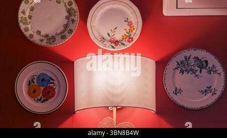 Decorative Wall Display of Plates and Lamp on a Red Background Stock Photo