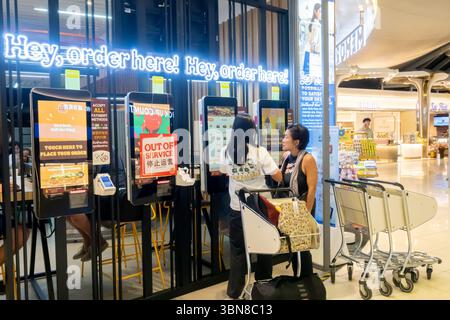 Female tourists ordering food, Customers making order through touchscreen device in Burger King cafe, Bangkok airport, Thailand Stock Photo