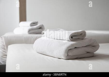 Bright luxury hotel bedroom interior clean white bed with plush pillows , soft blankets crisp linen bedding bright inviting light with sleek furniture Stock Photo