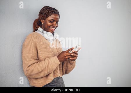 Portrait of young black woman who is messaging on smartphone. Stock Photo