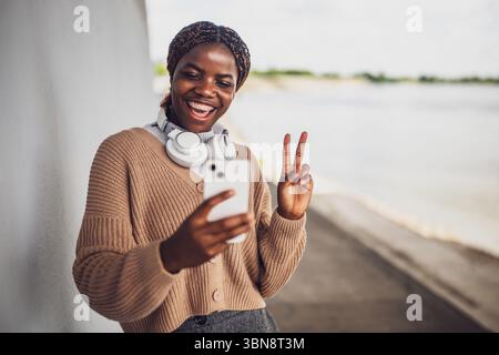 Portrait of young black woman who is having video call on smartphone. Stock Photo