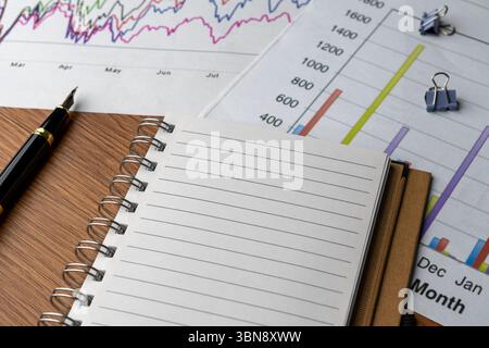 Financial charts and graphs with notebook on table. Business analysis, financial planning, status report, data interpretation concept. Stock Photo