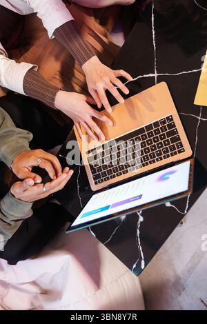 Multi ethnic team analyzing charts on laptop, coworkers discussing data in meeting Stock Photo