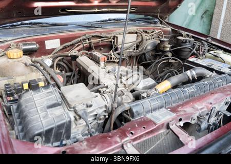 Close-up of an old Nissan vehicle with its hood open, showing engine components. Concept of car maintenance, repair, and vintage automobiles. Stock Photo