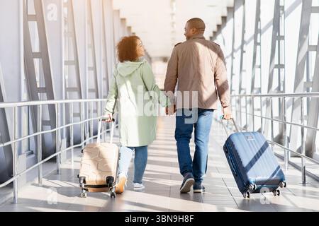 Travelling Together. Romantic African American Couple With Luggage Walking In Airport Terminal Stock Photo