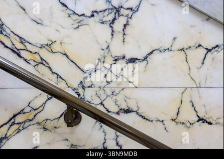 A polished handrail runs along a wall of veined white marble at Old City Hall, showcasing intricate dark patterns. Stock Photo