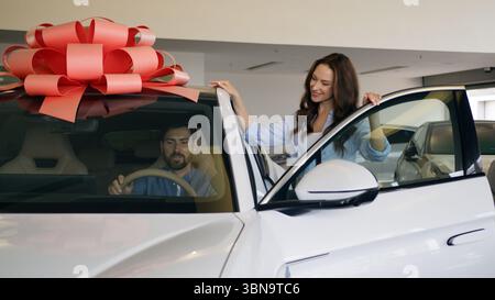 Happy Caucasian family buying new car luxury automobile choosing talking walking man open doors sitting inside auto trying test drive discuss couple Stock Photo