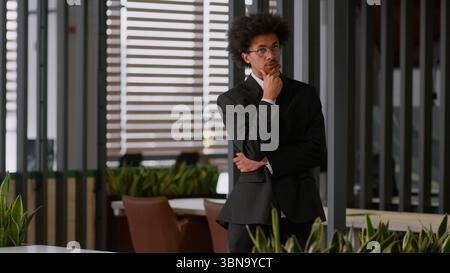 Pensive thoughtful puzzled thinking African American businessman employer developer employer business man male guy walk going walking in office ponder Stock Photo