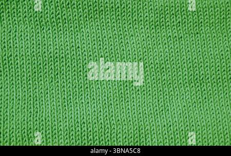 A detailed macro shot shows a green knit fabric. The stockinette stitch with neat vertical V-shaped patterns creates a soft, even and textured surface Stock Photo