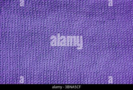 A detailed macro shot shows a purple knit fabric. The stockinette stitch with neat vertical V-shaped patterns creates a soft, even and textured surfac Stock Photo