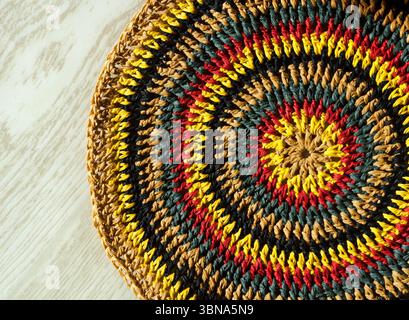 Beautiful crochet pattern made of raffia on a wooden background. Bottom for a beach bag or for decoration. Stock Photo