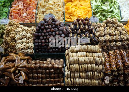 Istanbul, Turkey. The largest city in Turkey and one of the world’s few transcontinental cities, spanning both Europe and Asia across the Bosphorus Strait., A vibrant display of various dried fruits and nuts in a market stall. The stall is divided into multiple sections, each showcasing a different type of dried fruit or nut. The top left section features dried apricots, while the top right section displays dried green onions. The center section is filled with a variety of dried fruits, including dates, figs, and possibly other types of dried fruits. The bottom left section is filled with a Stock Photo