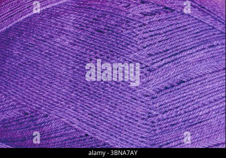 The texture of the lilac wool ball shows the tightly twisted threads. The details highlight the soft, fibrous quality of the material. Stock Photo