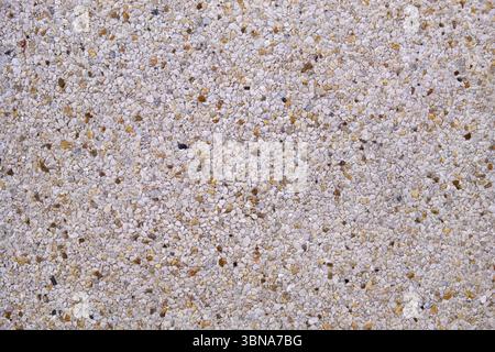 Light gray exposed aggregate concrete in closeup - pattern with some brown stones Stock Photo