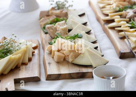 Cheese platter presenting a variety of cheeses, served with honey, arranged on wooden cutting boards for a catered event Stock Photo