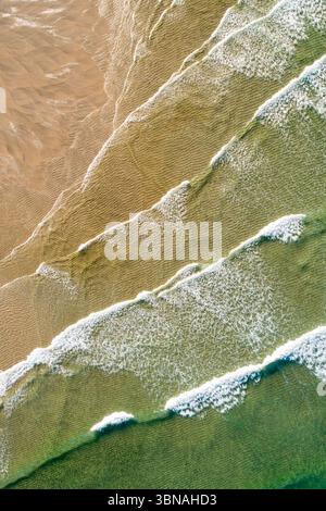 aerial view of diagonal waves creating natural patterns on a beach Stock Photo