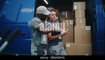 Outside of Logistics Distribution Warehouse: African American Employee and Female Inventory Manager Talking, Using Digital Tablet, Standing near Delivery Truck with Cardboard Boxes with Online Orders. Stock Photo
