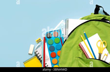 Top view of school backpack and school supplies with space for text over blue background. Back to school concept Stock Photo