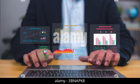 Businessman interacting with a futuristic virtual data analytics dashboard on a laptop, Key performance indicators, charts, business reports for strat Stock Photo