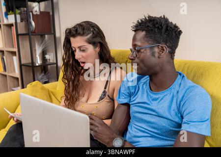 A young couple has a shocked reaction while reviewing their financial documents or bills at home. Stock Photo