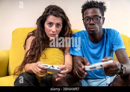 A young couple looks intently at the camera, holding game controllers, ready for a competitive video game match. Stock Photo
