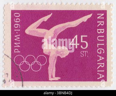 BULGARIA — 1960 August 29: 45 stotinki deep plum and pink postage stamp depicting Woman Gymnast. 17th Olympic Games, Rome, 25 August — 11 September. The Bulgarian Olympic Committee was created in 1923 and first sent a team to the Summer Olympic Games in 1924. The nation has participated in every Summer Games since then, except for 1932 (during the Great Depression), 1948 (Bulgaria's role in World War II) and 1984 (part of the Soviet-led boycott of the 1984 Summer Olympics) Stock Photo