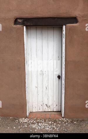 An old weathered white door framed by an adobe wall. Stock Photo