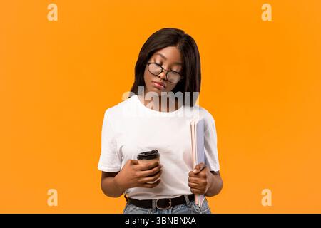 Tired black lady student with books sleeping on orange Stock Photo