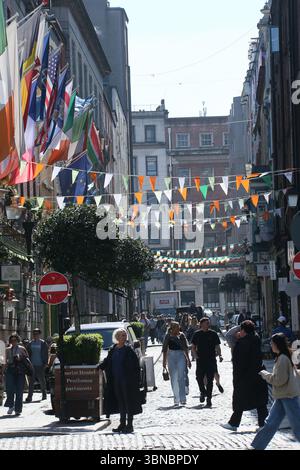 Dublin, Ireland  - 8th April 2025 - Irish themed green, white and orange bunting and tricolour flags hang over a street in Temple Bar, Dublin city centre on a sunny day Stock Photo