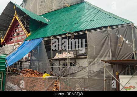 A historic Thai building under construction, part of the Royal Palace complex covered in scaffolding and protective tarps. Bangkok, Thailand Stock Photo