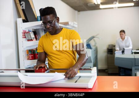 Employee of printing house checks the quality of printing in computer room Stock Photo