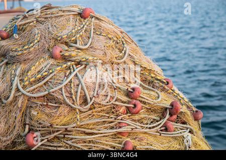 Vibrant fishing nets and buoys piled on a dock, ready for the sea, closeup Stock Photo