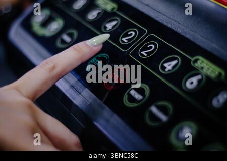 A close-up captures a finger pressing the control panel of a treadmill. The focus is on the activation and engagement with the machine, highlighting f Stock Photo