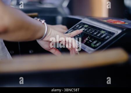 A woman's hands adjusting settings on a treadmill control panel, preparing for her indoor fitness workout. Focus on health, active lifestyle and moder Stock Photo