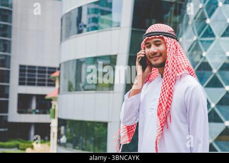 Islamic man using smartphones app organize schedule agenda  focus on hands holding smartphone muslim modern uae city. Arab men wear hijab and muslim f Stock Photo