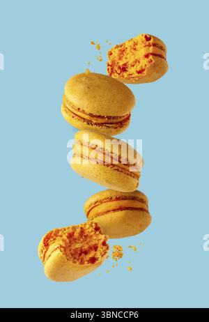 French dessert - yellow macaroons flying on a blue background, selective focus Stock Photo