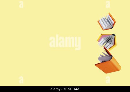 Books in colored covers and school supplies are flying on a yellow background Stock Photo