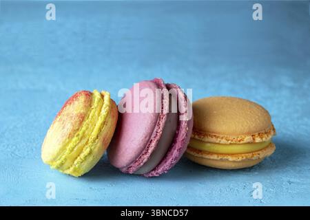 Yellow and purple macaroons lie on a blue background, selective focus Stock Photo
