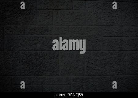 rough-textured dark gray stone brick wall is showcasing flat design with chiseled marks and shadows Stock Photo