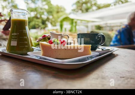Tray of food with a green container on the left. The tray has a slice of cake and a cup of coffee Stock Photo