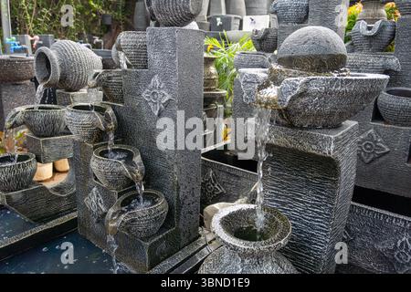 Large fountain with many small fountains and a wall of bricks. The water is flowing from the top of the wall Stock Photo