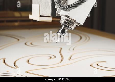 four-axis numerically controlled woodworking machine cuts out complex lines on the canvas. CNC, computer control. Stock Photo
