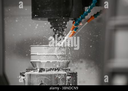 The CNC milling machine cutting the mold parts with oil coolant method. The mold and die manufacturing process by CNC machining center. Stock Photo