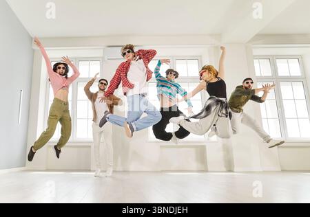 Young people full of energy jumping high in air, practicing dance in studio Stock Photo