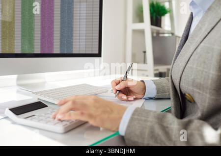Financial accountant calculating expenses and reviewing financial spreadsheet on computer screen. Stock Photo