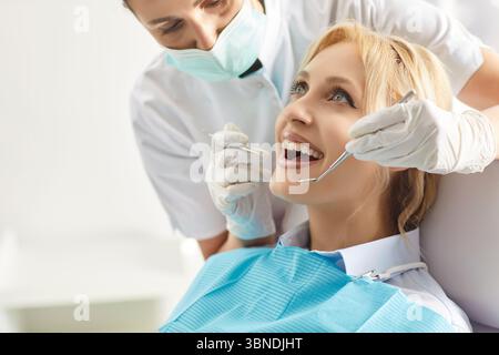 Professional woman stomatologist using dental tools for curing teeth of female patient. Stock Photo