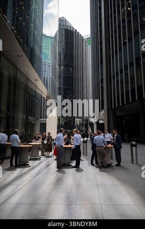 City workers in the financial district of the City of London enjoying the warm temperatures whilst having a coffee break on Leadenhall Street, England. Stock Photo