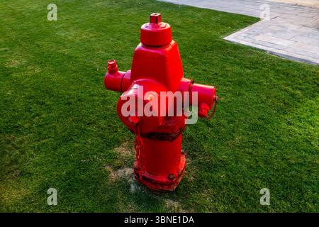 A bright red fire hydrant standing on a sidewalk, symbolizing safety and emergency response. A common urban element with bold color and industrial des Stock Photo