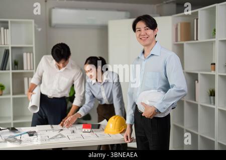 Project Management and Team Dynamics. A dedicated group mapping out their construction plans in a modern office setup. Stock Photo